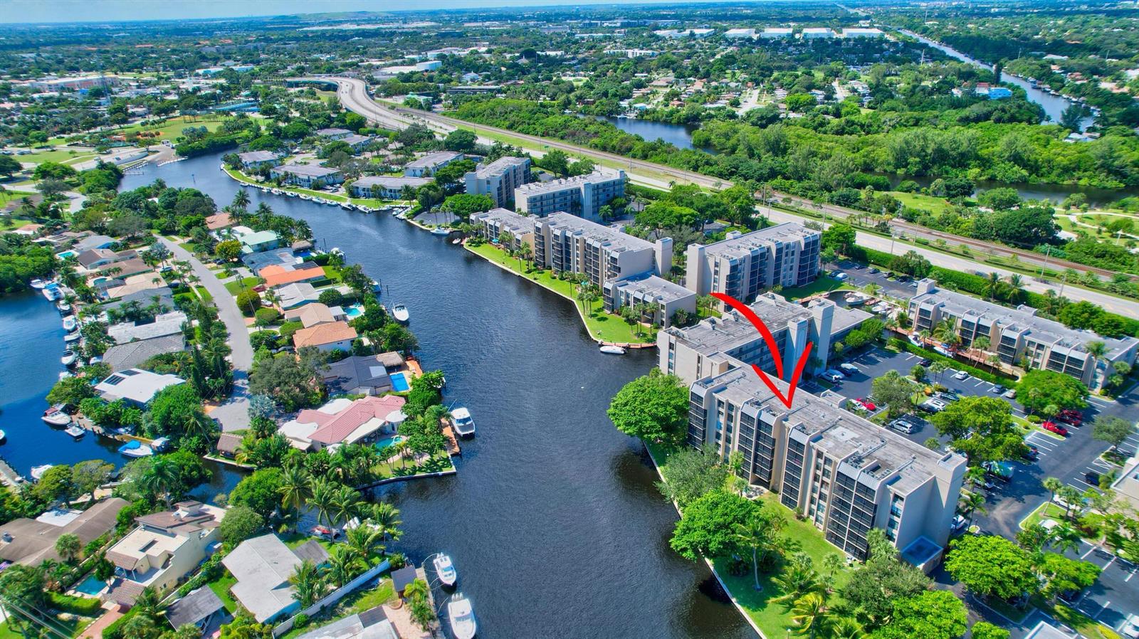 An aerial view shows a multi-story apartment complex situated along a canal with boats — 14 Royal Palm Way # 2050, Boca Raton FL 33432, BOCA RATON, FL