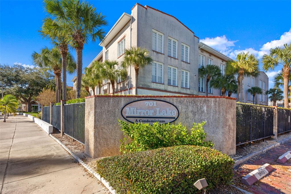 The exterior of a multi-story condominium building with a prominent sign and palm trees — 701 MIRROR LAKE DRIVE N UNIT 201, ST PETERSBURG, FL