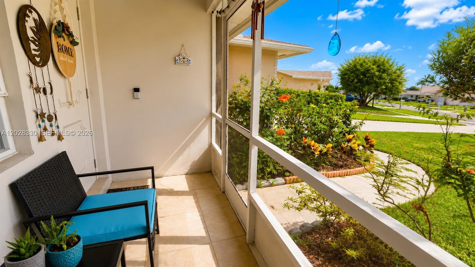 A screened-in porch features a chair, tiled floor, and a view of a landscaped yard — 13190 Via Vesta, Delray Beach FL 33484, DELRAY BEACH, FL