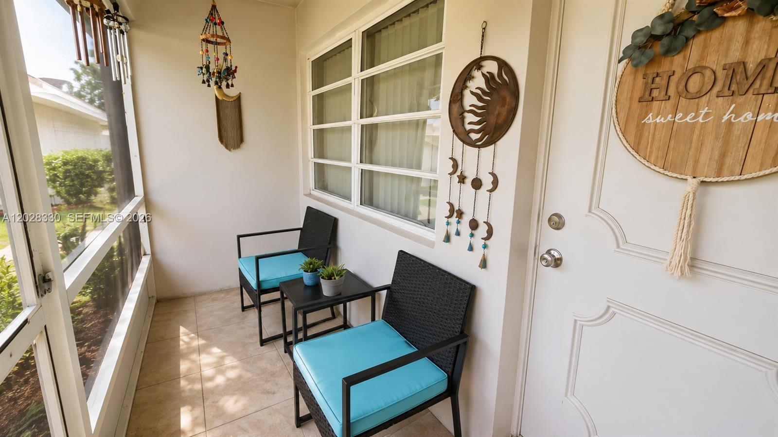 A screened-in porch features two black chairs with blue cushions and a small side table — 13190 Via Vesta, Delray Beach FL 33484, DELRAY BEACH, FL