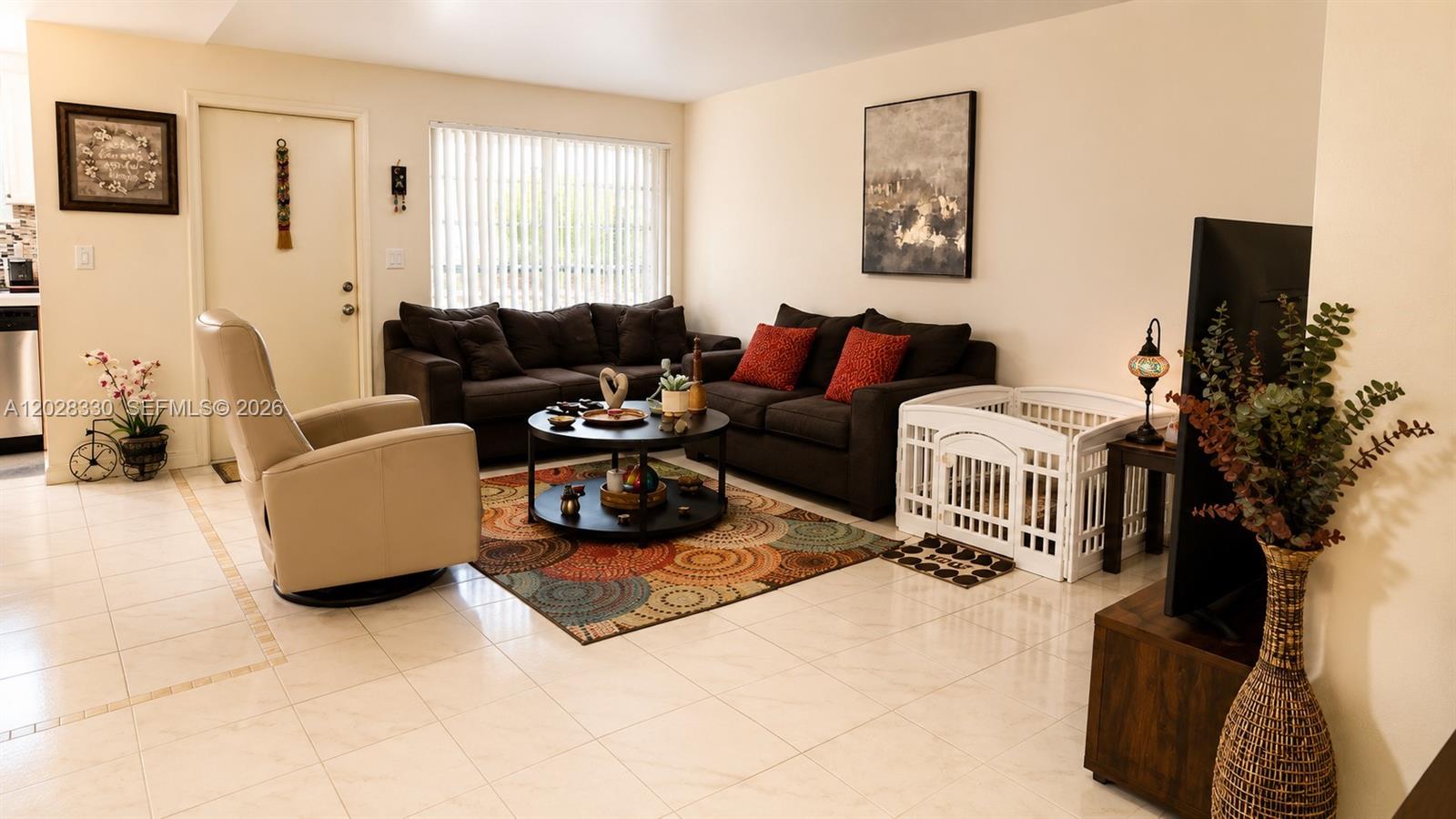 A living room features tile flooring, a dark sofa, a round coffee table, and a pet pen — 13190 Via Vesta, Delray Beach FL 33484, DELRAY BEACH, FL