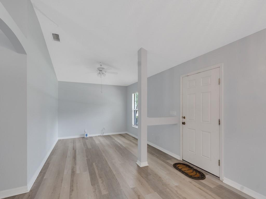 An empty room with light gray walls, wood-look flooring, a ceiling fan, and a support post — VERO BEACH, FL
