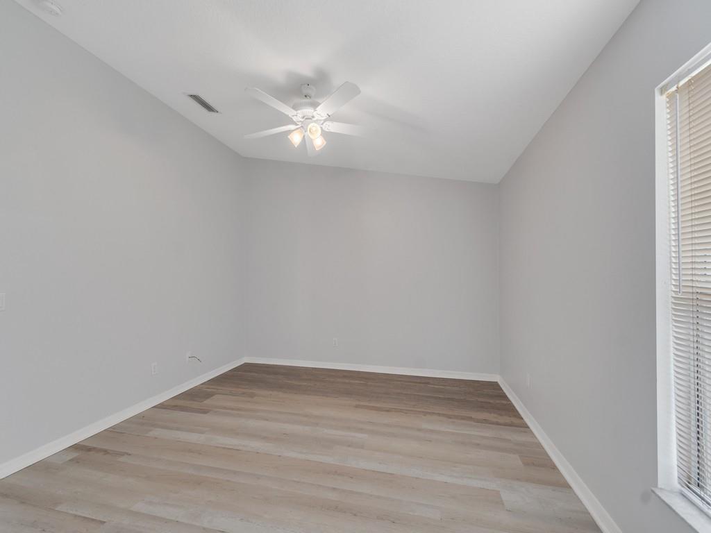 An empty room features light gray walls, wood-look flooring, and a white ceiling fan — VERO BEACH, FL