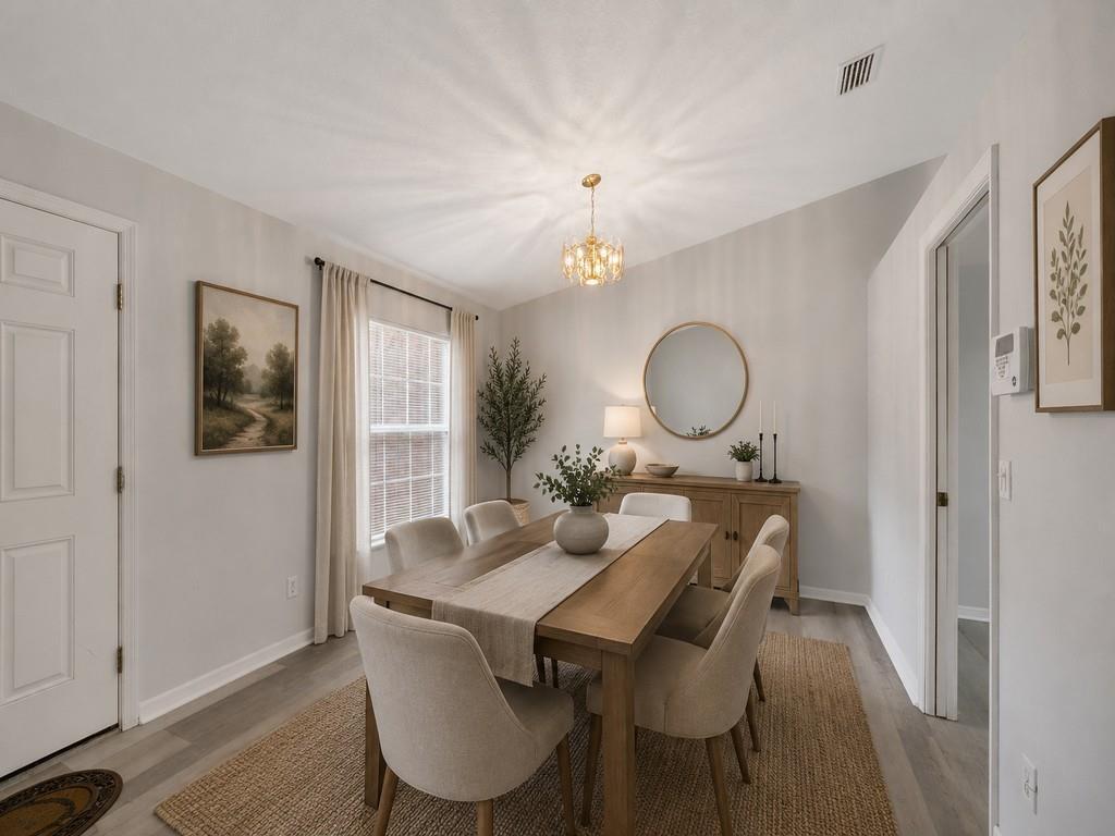 A dining room features a wooden table, upholstered chairs, a round mirror, and a chandelier — VERO BEACH, FL
