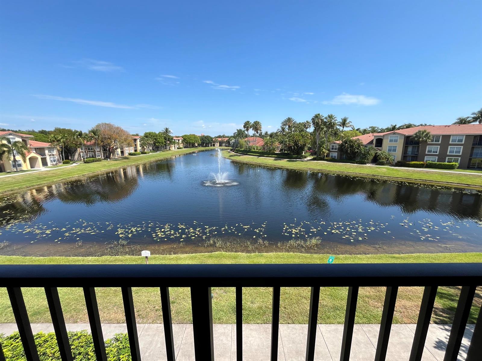 A view from a balcony overlooking a pond with a fountain and surrounding apartment buildings — 15135 Michelangelo Boulevard # 306, Delray Beach FL 33446, DELRAY BEACH, FL
