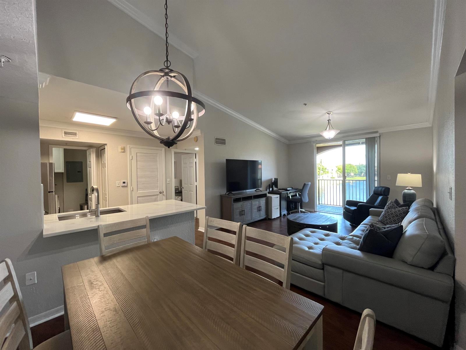 An open-concept living and dining area features a kitchen island, vaulted ceilings, and balcony access — 15135 Michelangelo Boulevard # 306, Delray Beach FL 33446, DELRAY BEACH, FL