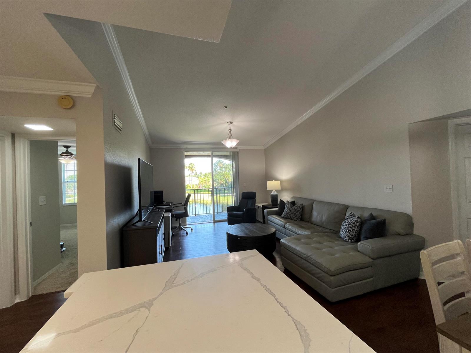 A living room with a gray sectional, dark wood floors, and a balcony overlooking water — 15135 Michelangelo Boulevard # 306, Delray Beach FL 33446, DELRAY BEACH, FL