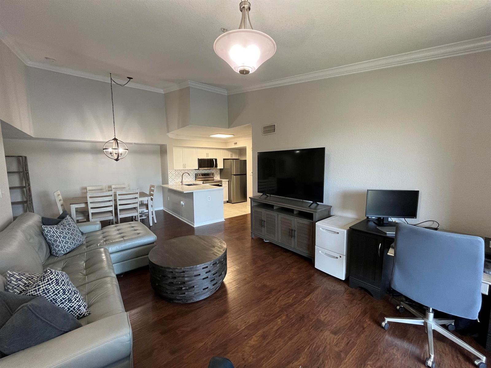 An open-concept living room features a sectional sofa, dining area, kitchen, and home office space — 15135 Michelangelo Boulevard # 306, Delray Beach FL 33446, DELRAY BEACH, FL