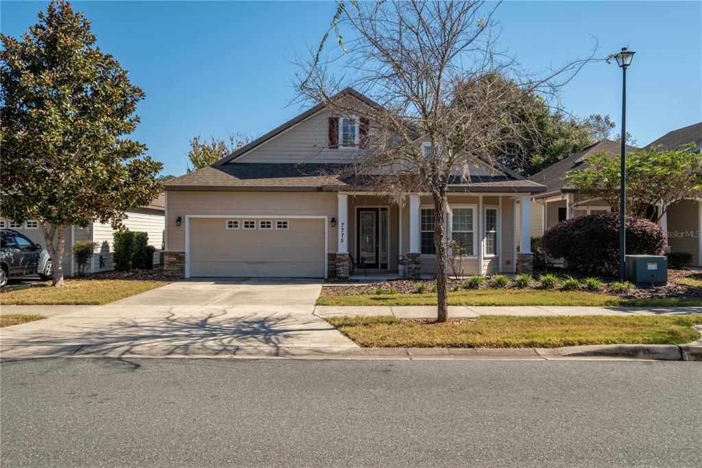 A two-story suburban house with a tan exterior, a two-car garage, and a front porch — 7775 SW 80TH DRIVE, GAINESVILLE, FL