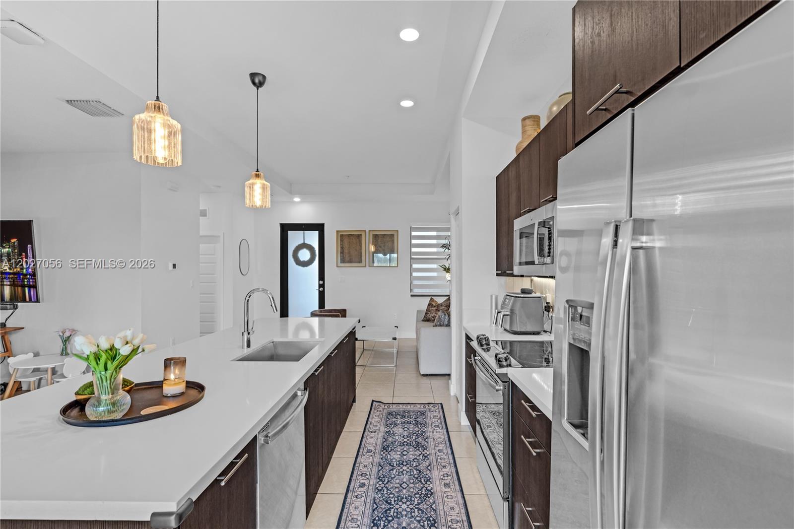 A modern kitchen features dark wood cabinets, white countertops, stainless steel appliances, and pendant lighting — 8175 NW 104th Ave # 32, Doral FL 33178, DORAL, FL