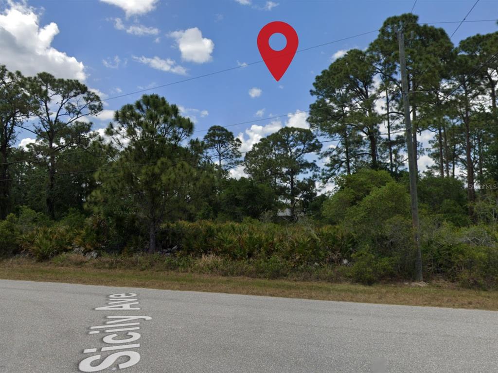 A paved road runs in front of a wooded lot marked by a red location pin — 18090 SICILY AVENUE, PORT CHARLOTTE, FL