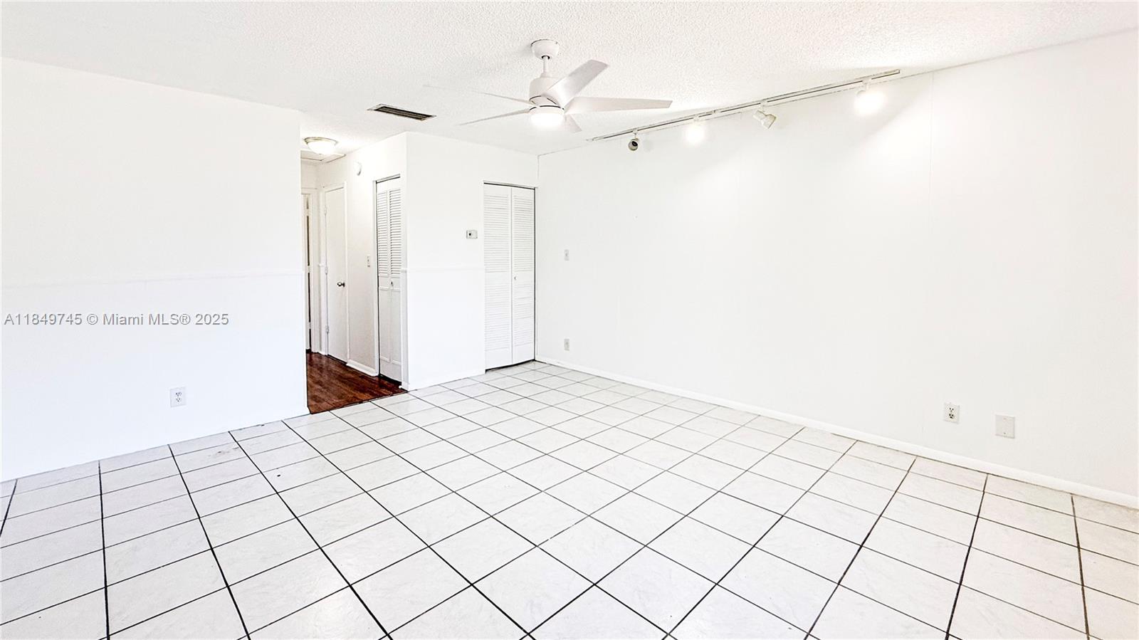A white-walled room features white tile flooring, a ceiling fan, and track lighting — 3200 NW 5th Ter # 8, Pompano Beach FL 33064, POMPANO BEACH, FL