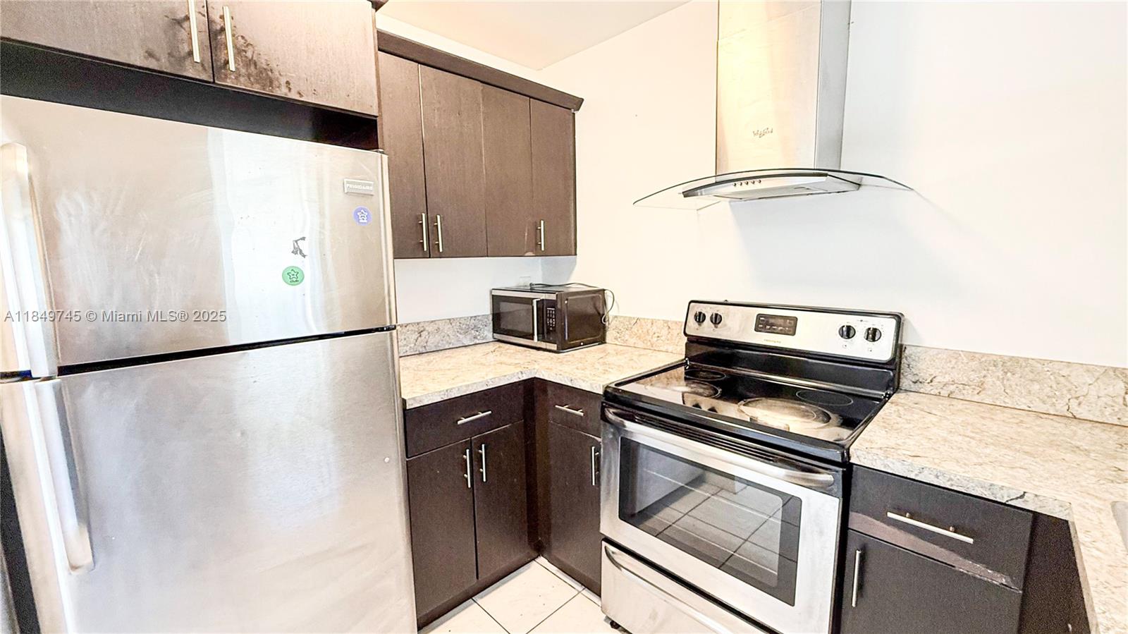 A kitchen features dark wood cabinets, stainless steel appliances, and light-colored granite countertops — 3200 NW 5th Ter # 8, Pompano Beach FL 33064, POMPANO BEACH, FL