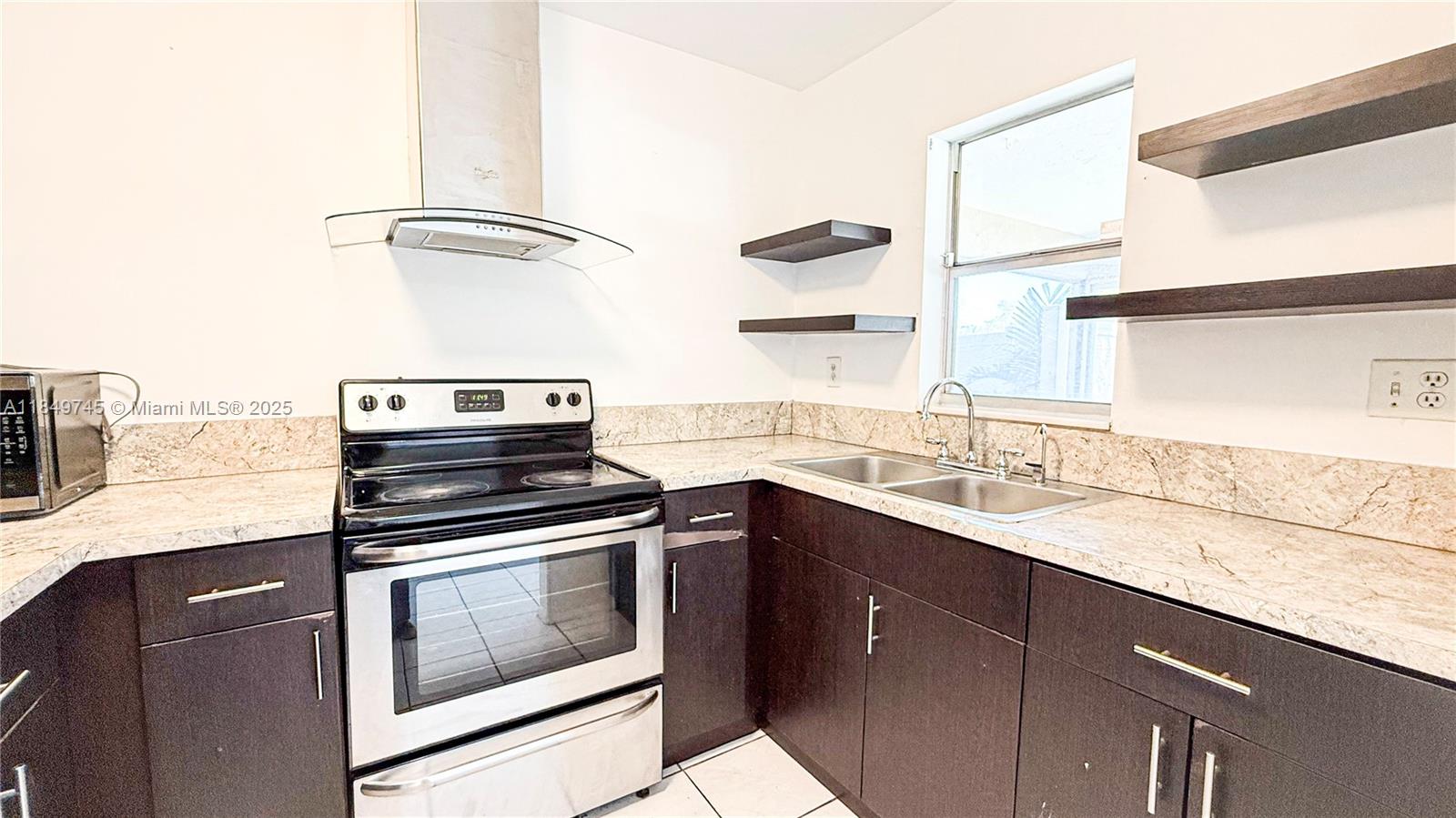 A kitchen features dark wood cabinets, granite countertops, a stainless steel stove, and open shelving — 3200 NW 5th Ter # 8, Pompano Beach FL 33064, POMPANO BEACH, FL