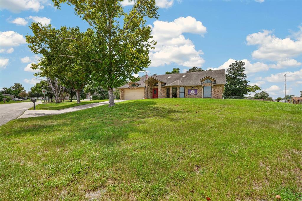 A single-story brick house with a red front door sits on a large grassy lot — 1862 PORTVIEW AVENUE, DELTONA, FL