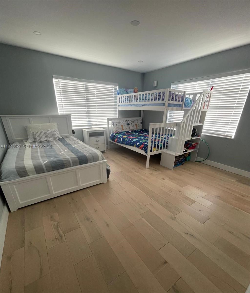 A staged bedroom features light wood floors, gray walls, a bed, and a floor mirror — 1235 Pennsylvania Ave # 4E, Miami Beach FL 33139, MIAMI BEACH, FL