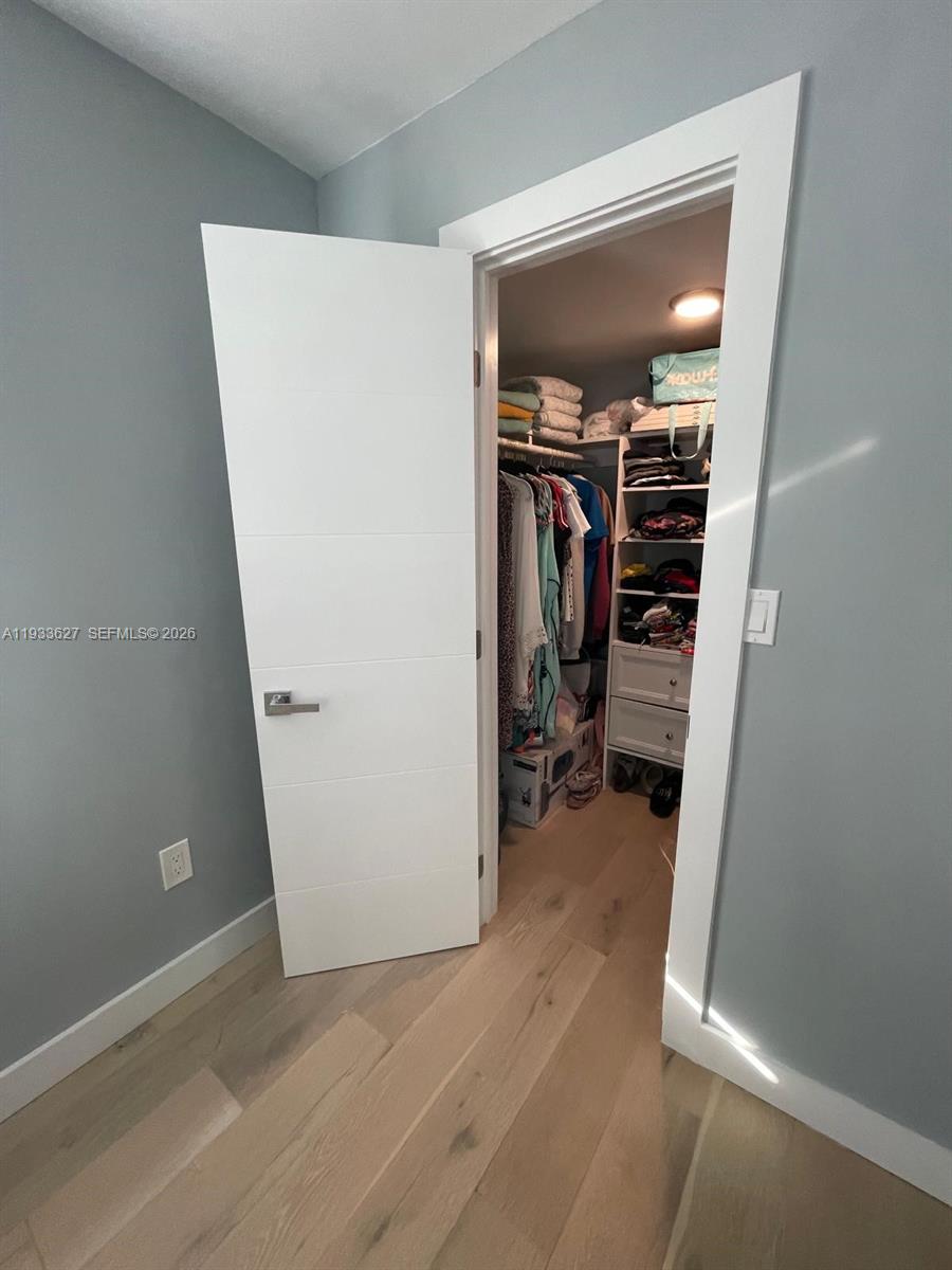 A white door opens into a walk-in closet with shelving and hanging clothes — 1235 Pennsylvania Ave # 4E, Miami Beach FL 33139, MIAMI BEACH, FL