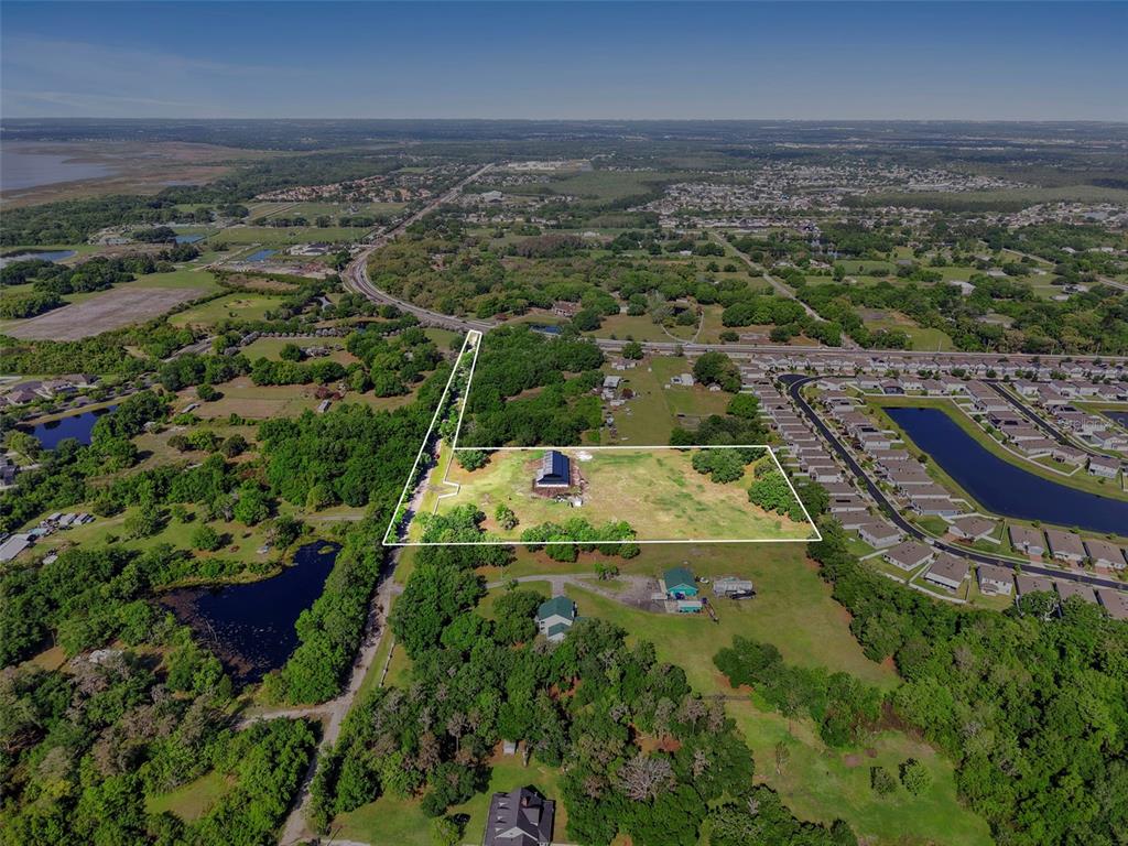 An aerial view shows a large, rectangular plot of land with a house and trees — 4355 SEMORAN FARMS ROAD, KISSIMMEE, FL