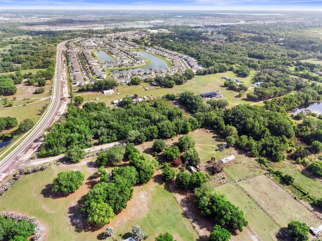 An aerial view shows a large, grassy lot with scattered trees near a residential neighborhood — 4355 SEMORAN FARMS ROAD, KISSIMMEE, FL