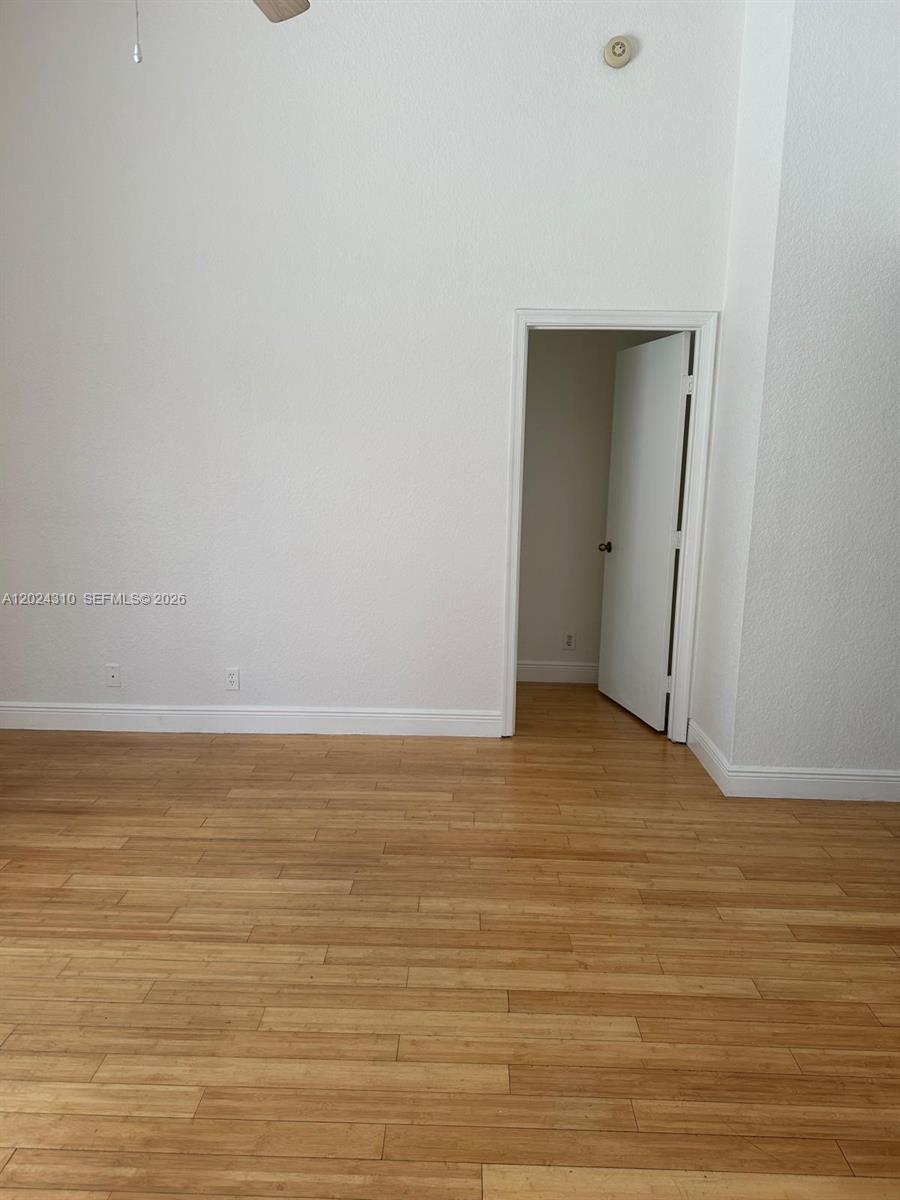 An empty room features light-colored wood flooring, white walls, and an open doorway — 11090 Baybreeze Way, Boca Raton FL 33428, BOCA RATON, FL