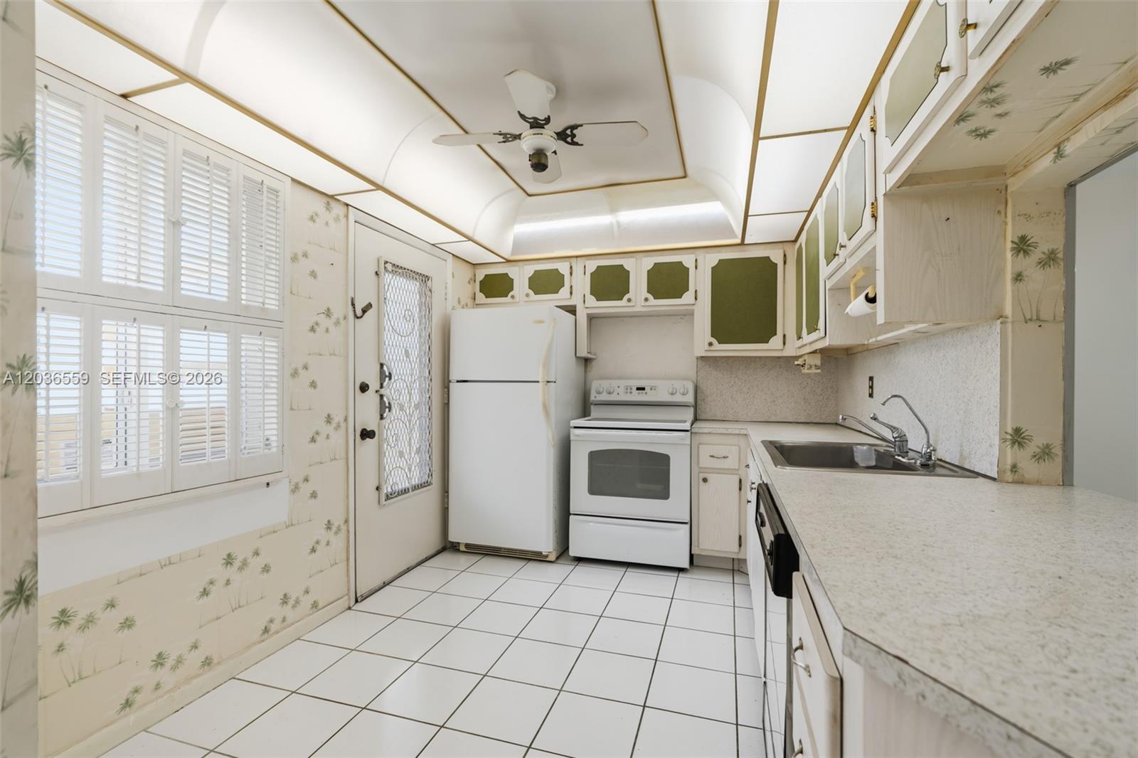 A kitchen features white appliances, tiled floors, patterned wallpaper, and a recessed ceiling light fixture — 1201 NE 191st St # G219, Miami FL 33179, MIAMI, FL