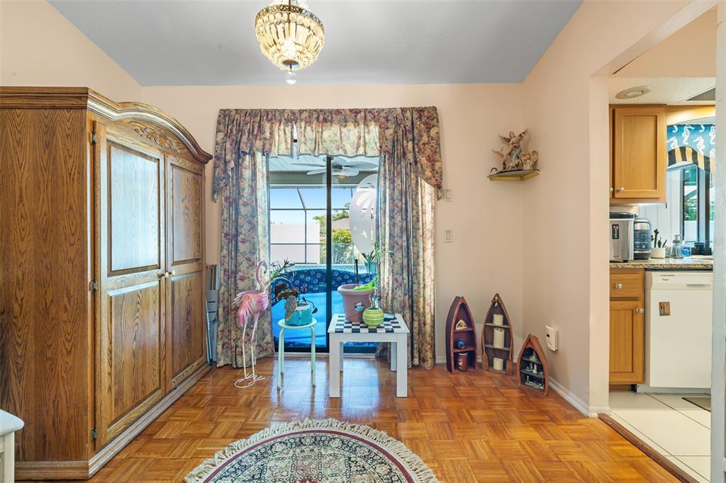 A dining area features parquet wood flooring, a large wooden armoire, and sliding glass doors — 2132 ABSCOTT STREET, PORT CHARLOTTE, FL