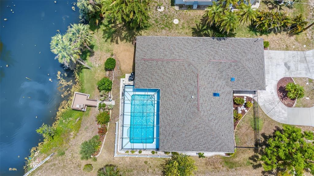 An aerial view shows a house with a screened-in pool, a dock, and a lake — 2132 ABSCOTT STREET, PORT CHARLOTTE, FL