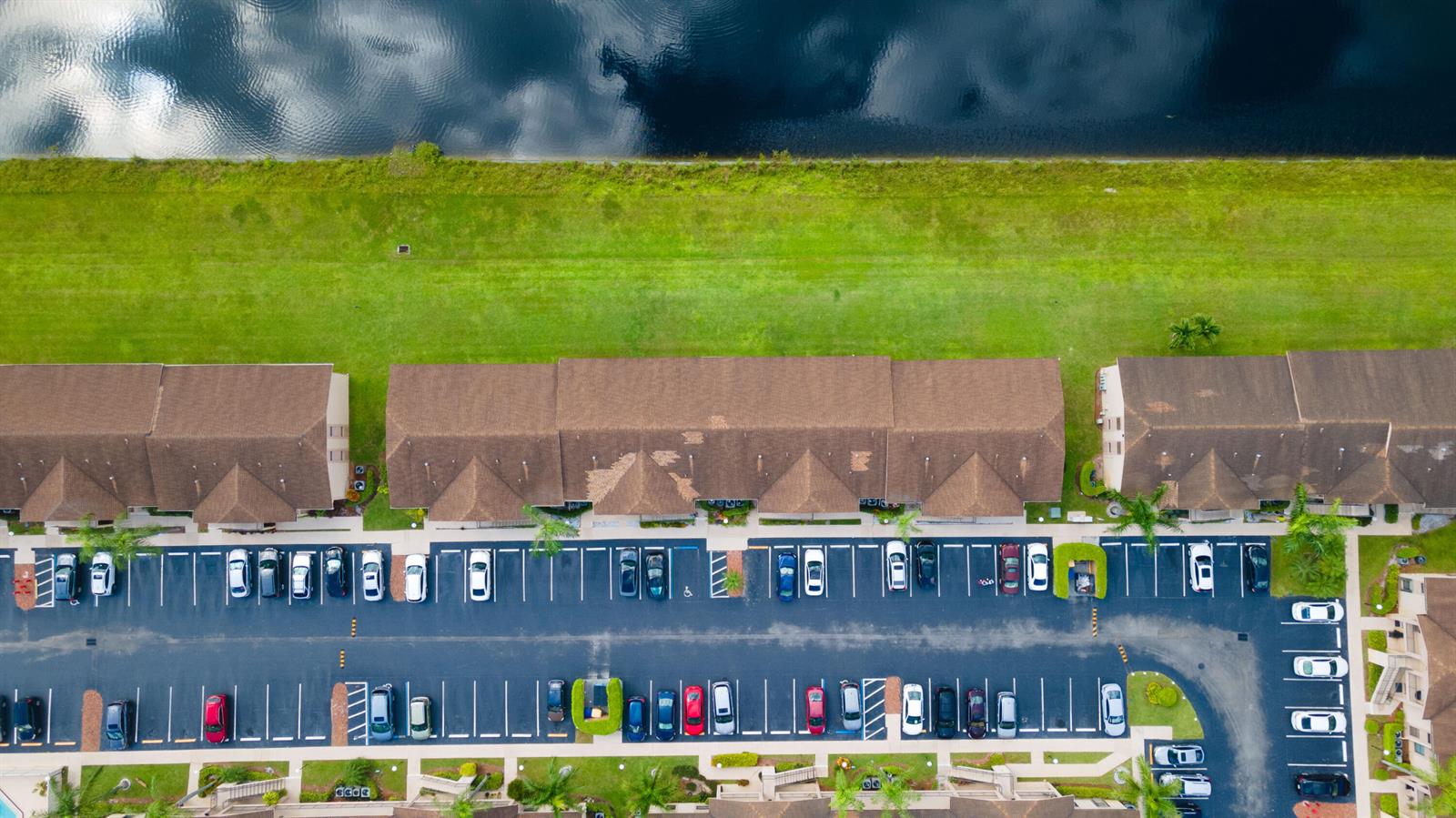 An aerial view shows a multi-unit residential building with parking lots and a nearby pond — 9467 Boca Cove Circle # 804, Boca Raton FL 33428, BOCA RATON, FL