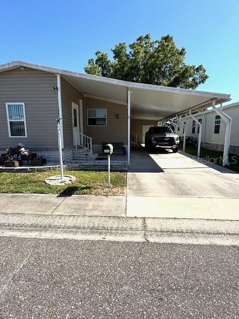 A single-story manufactured home features a large attached carport and a paved driveway — 1001 STARKEY RD. LOT 731, LARGO, FL
