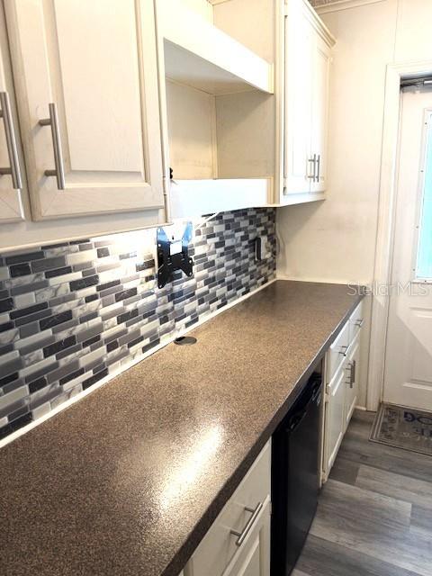 A kitchen features light-colored cabinets, a dark countertop, and a gray-toned mosaic tile backsplash — 1001 STARKEY RD. LOT 731, LARGO, FL