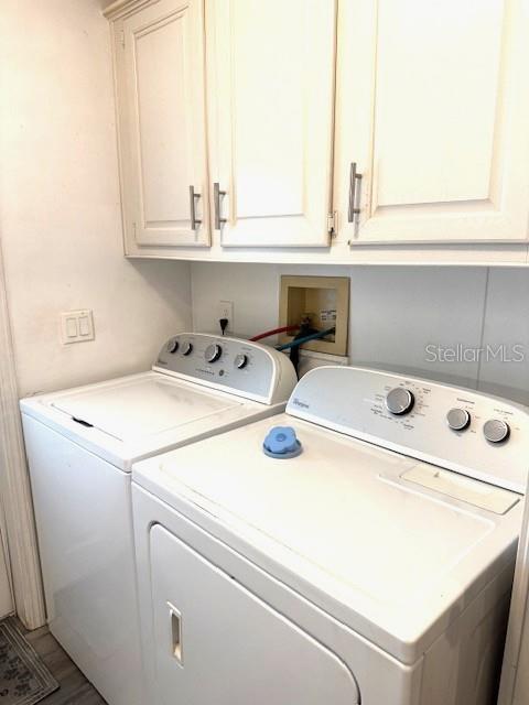 A laundry room features a white washer and dryer beneath white upper cabinets — 1001 STARKEY RD. LOT 731, LARGO, FL
