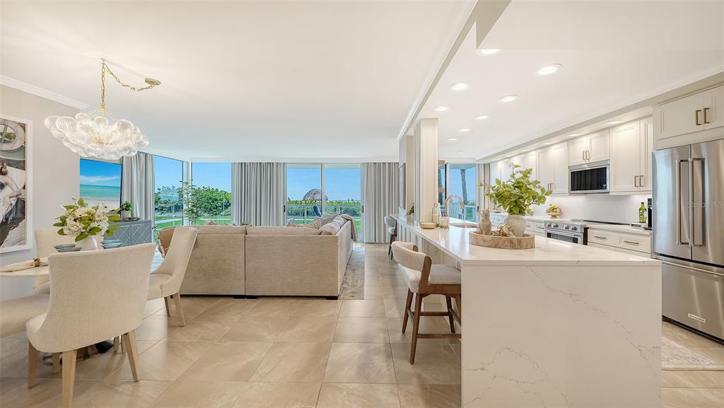 An open-concept living and dining area features a modern kitchen with white cabinetry and ocean views — 2425 GULF OF MEXICO DRIVE UNIT 1B, LONGBOAT KEY, FL
