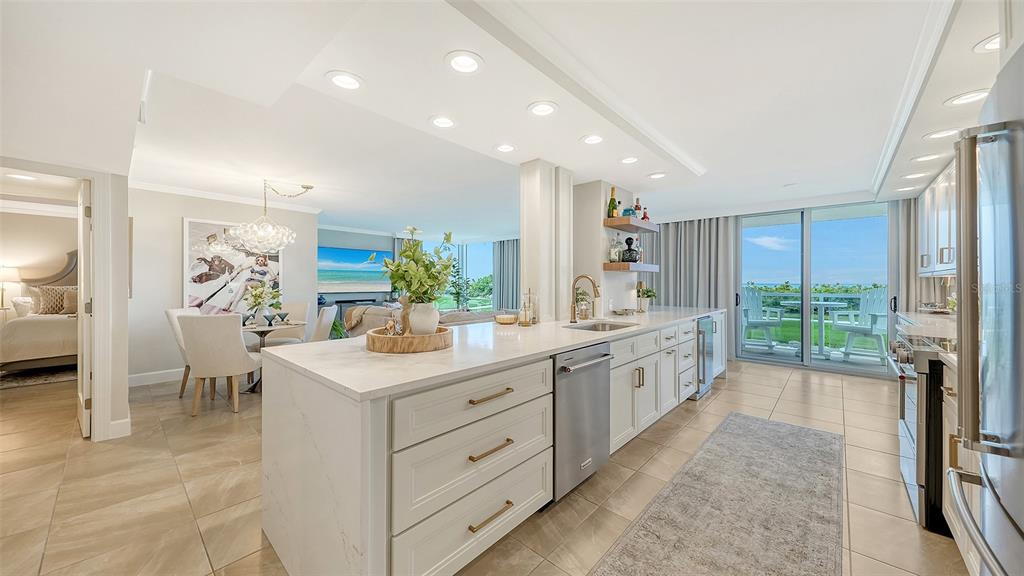 A modern kitchen with white cabinetry, marble countertops, and a large island overlooks a balcony — 2425 GULF OF MEXICO DRIVE UNIT 1B, LONGBOAT KEY, FL