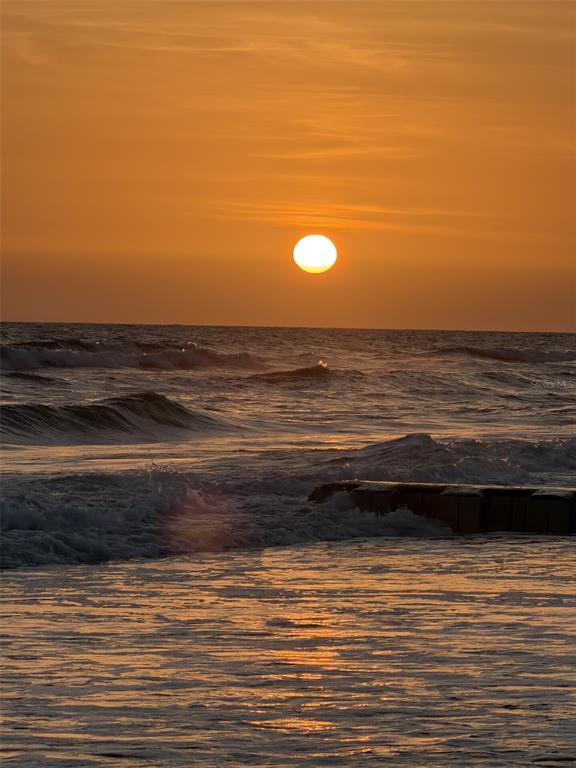 A sunset view over the ocean with waves crashing near a wooden pier structure — 11533 69TH AVENUE, SEMINOLE, FL