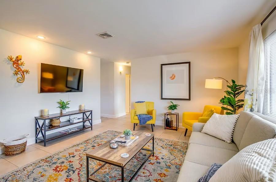 A living room features a television, a coffee table, a sofa, and two yellow armchairs — 11533 69TH AVENUE, SEMINOLE, FL