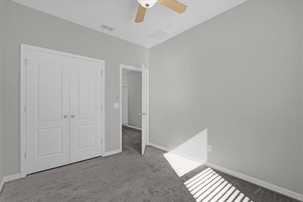 An empty bedroom with gray carpet, light gray walls, a ceiling fan, and two doors — 1148 PALMA VERDE PLACE, APOPKA, FL