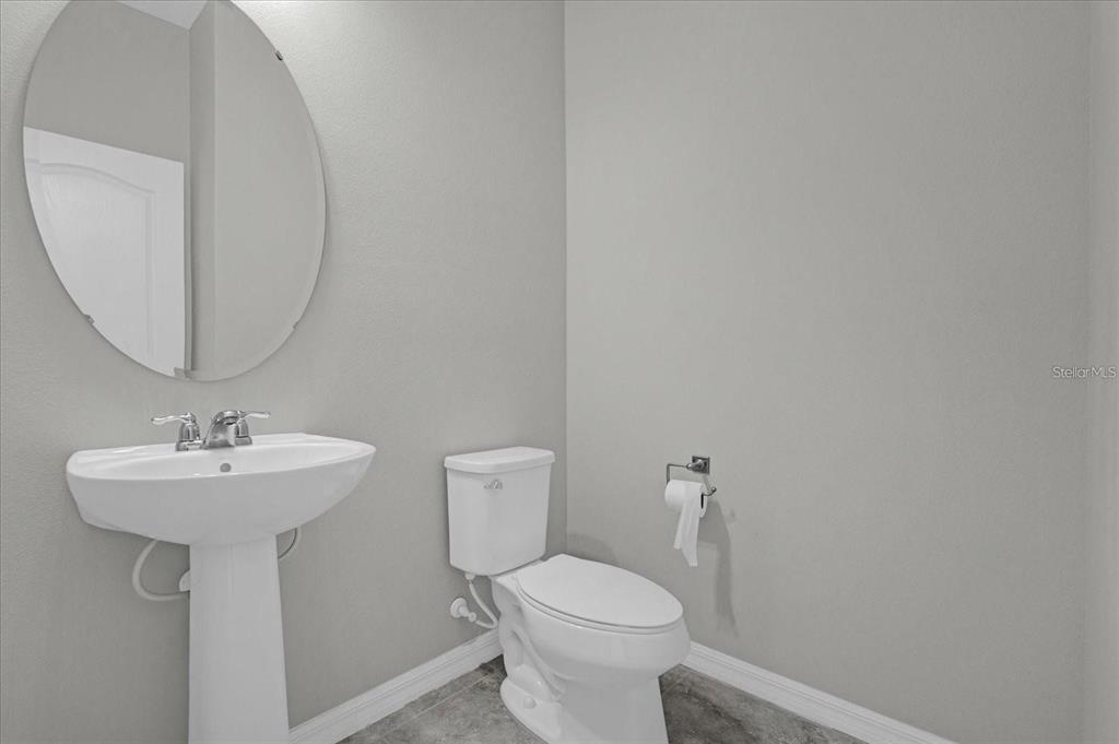 A half bathroom features a pedestal sink, an oval mirror, and a white toilet — 1148 PALMA VERDE PLACE, APOPKA, FL