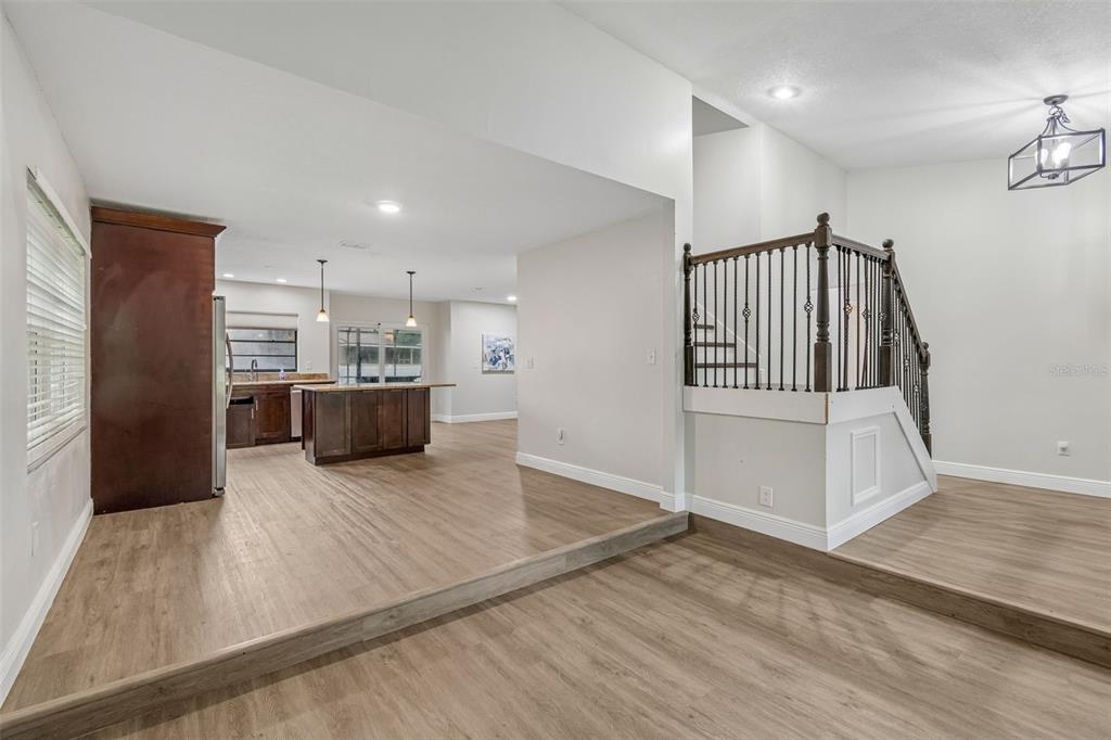 A split-level interior features a kitchen with dark cabinets and a staircase with iron railings — 16507 CRANWOOD PLACE, TAMPA, FL