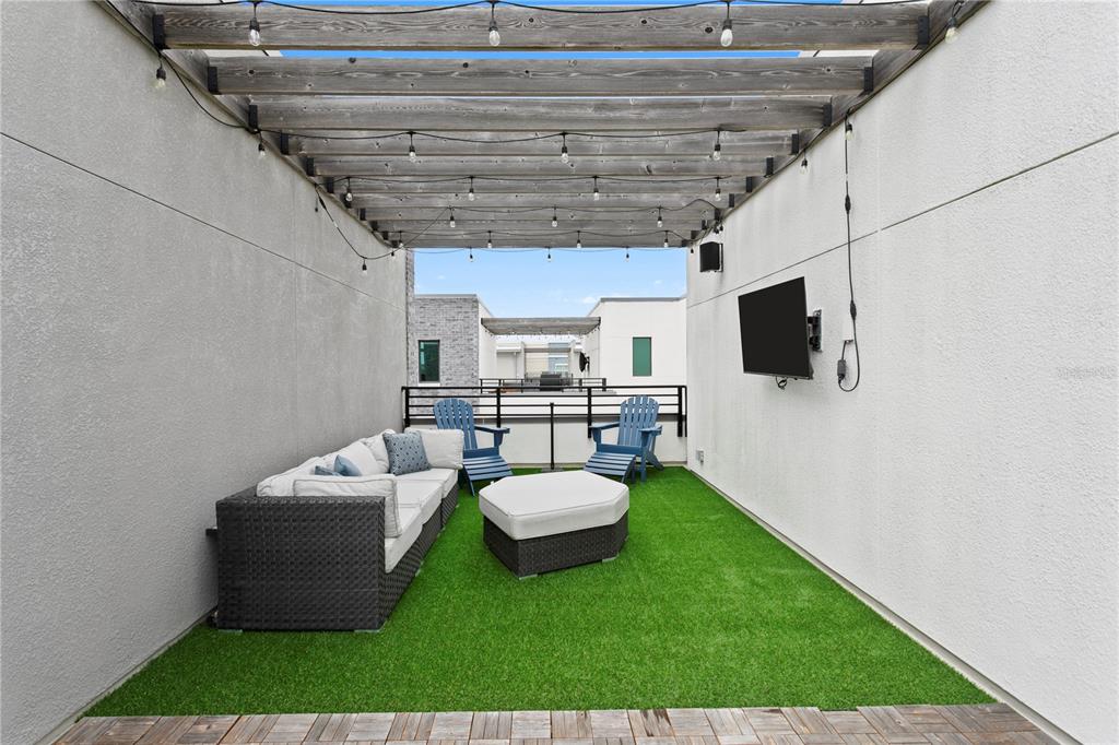 An outdoor rooftop patio features artificial turf, a pergola, lounge seating, and a wall-mounted television — 2511 N GRADY AVENUE UNIT 63, TAMPA, FL
