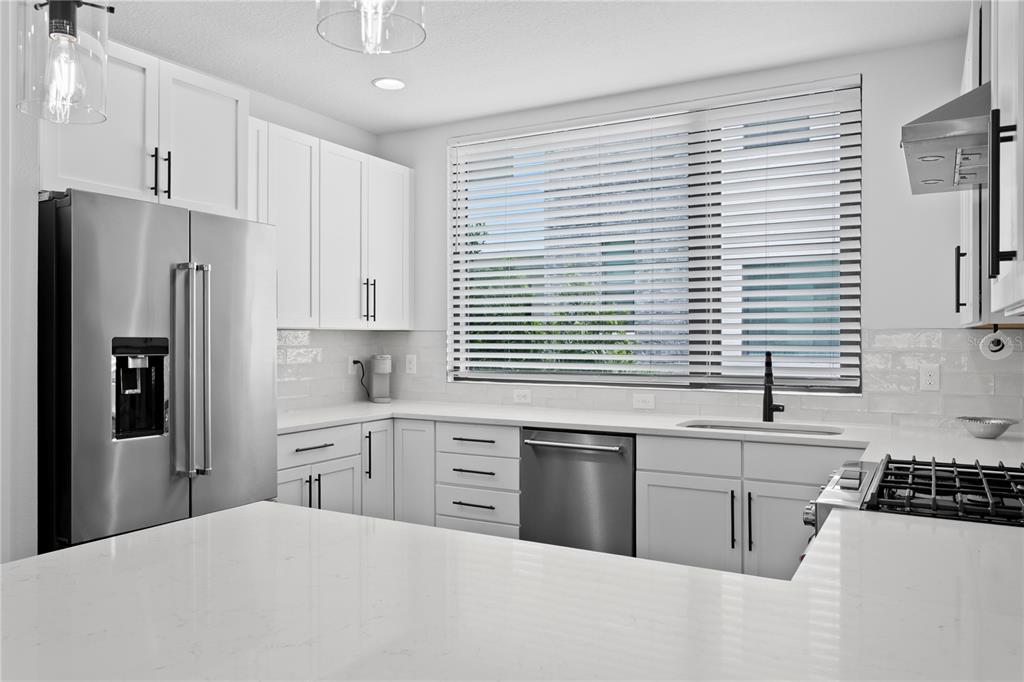 A modern kitchen features white cabinets, stainless steel appliances, and a white quartz countertop — 2511 N GRADY AVENUE UNIT 63, TAMPA, FL