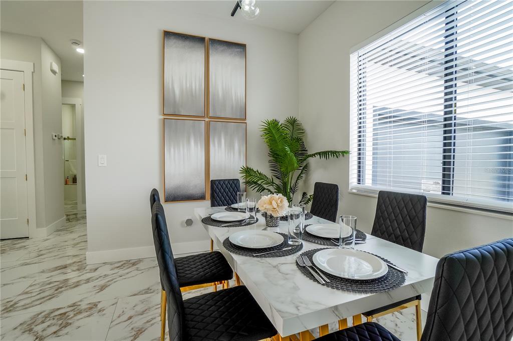 A dining room features a marble-topped table, black quilted chairs, and abstract wall art — 15561 MELPORT CIRCLE, PORT CHARLOTTE, FL