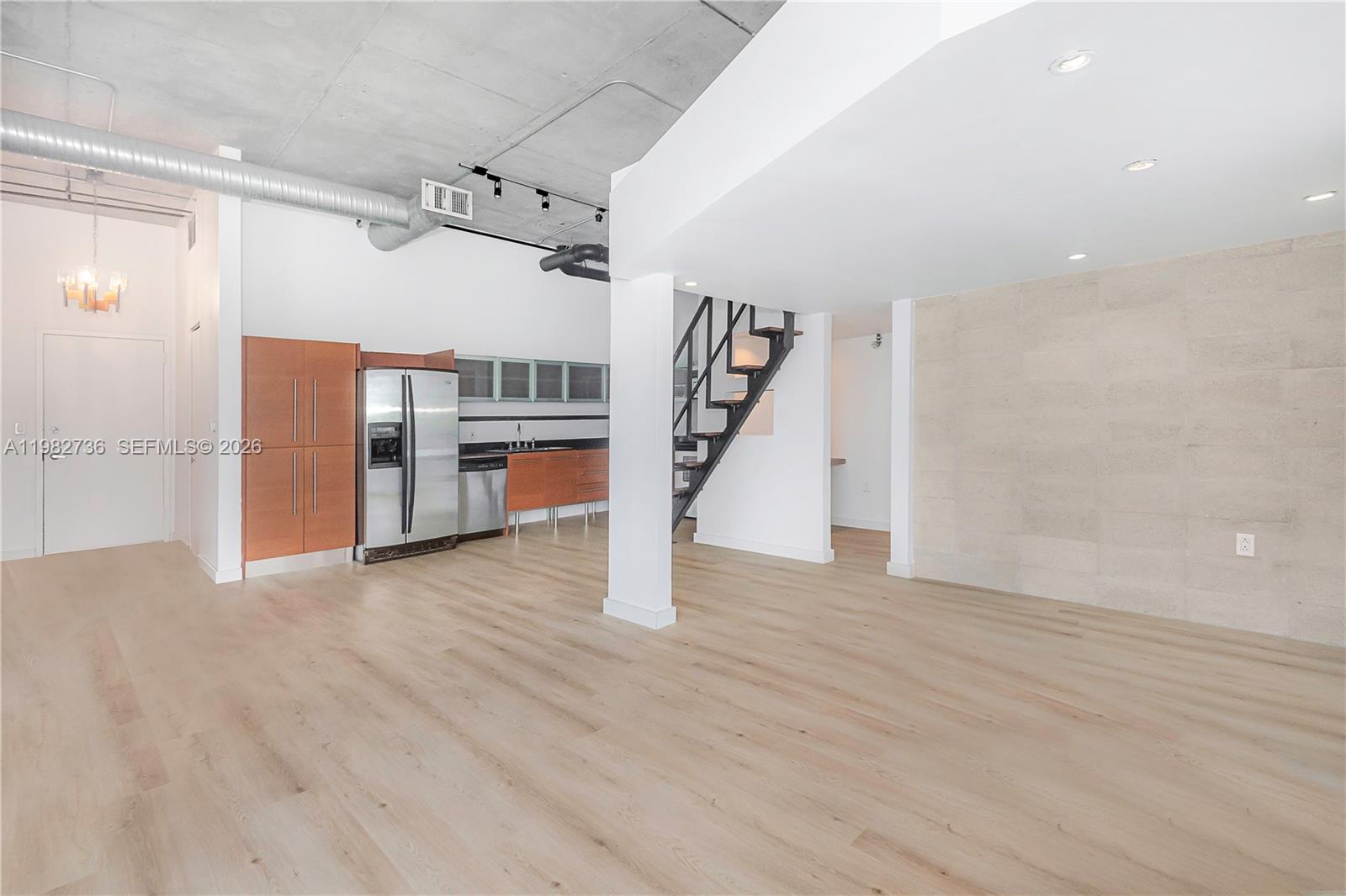 This open-concept living area features a kitchen, concrete ceiling, and a staircase — 10 SW South River Dr # 607, Miami FL 33130, MIAMI, FL