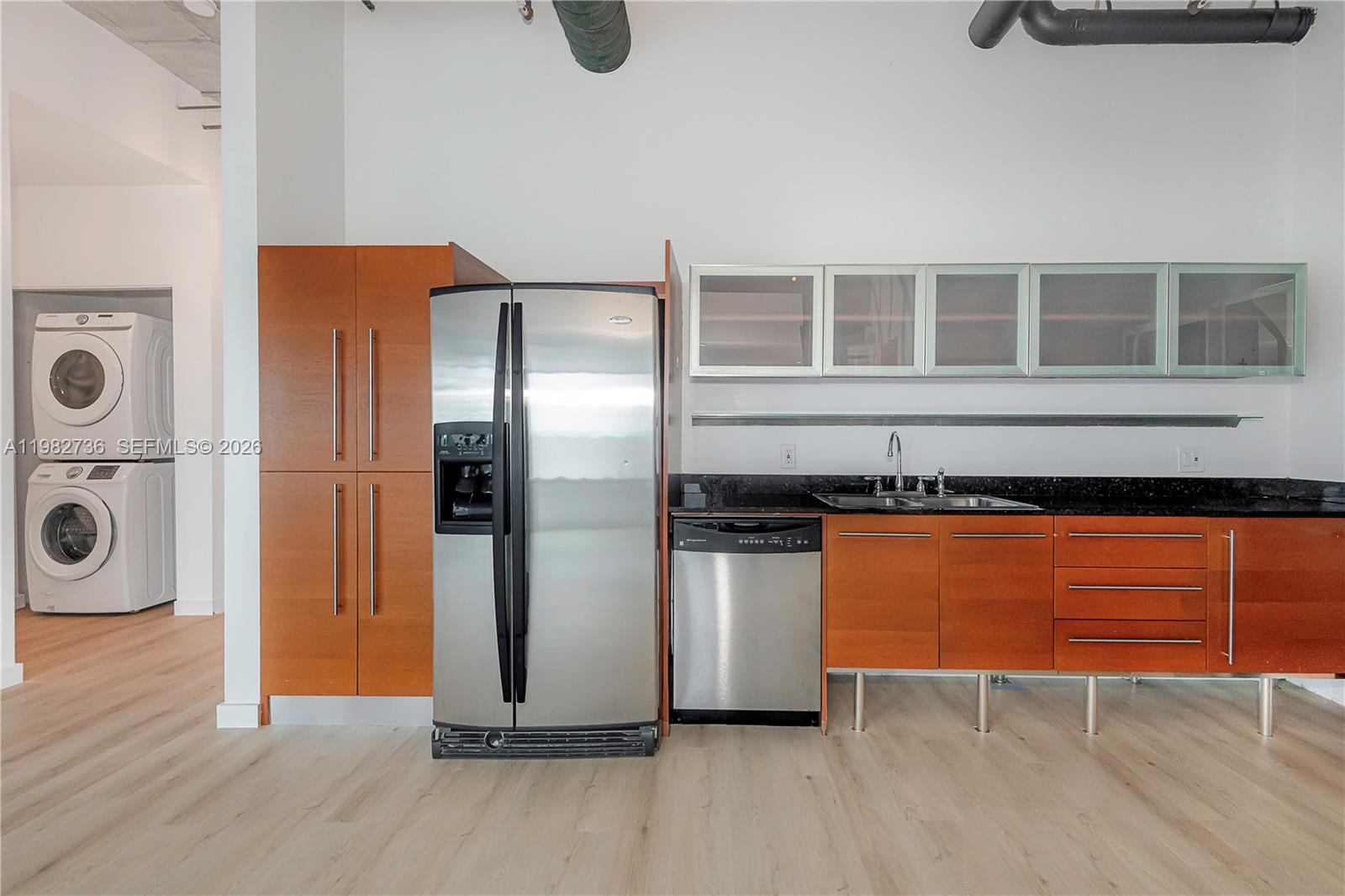 A kitchen features wood cabinets, stainless steel appliances, black countertops, and an adjacent laundry area — 10 SW South River Dr # 607, Miami FL 33130, MIAMI, FL
