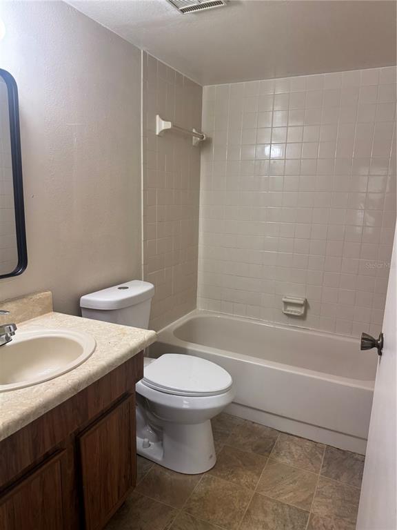 A bathroom features a vanity, a toilet, and a bathtub with white wall tiles — 3028 BONAVENTURE CIRCLE UNIT 103, PALM HARBOR, FL