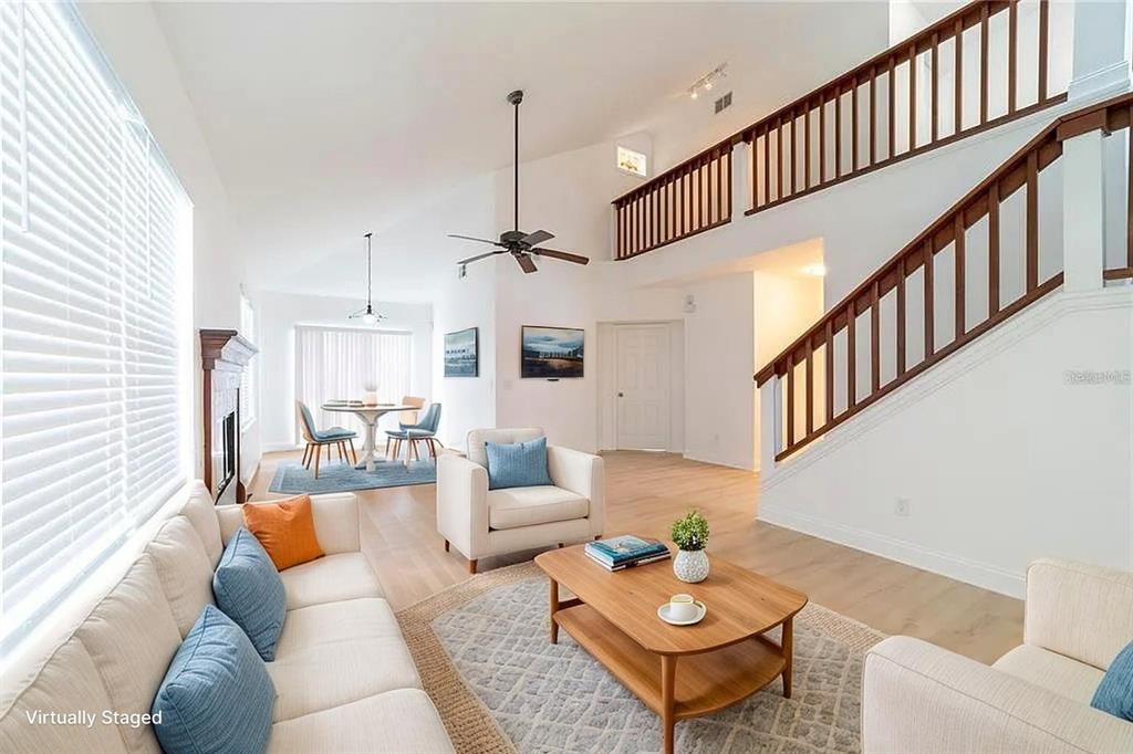 A living room with a vaulted ceiling, wooden staircase, and light-colored flooring — 499 JULIAN LANE, MAITLAND, FL