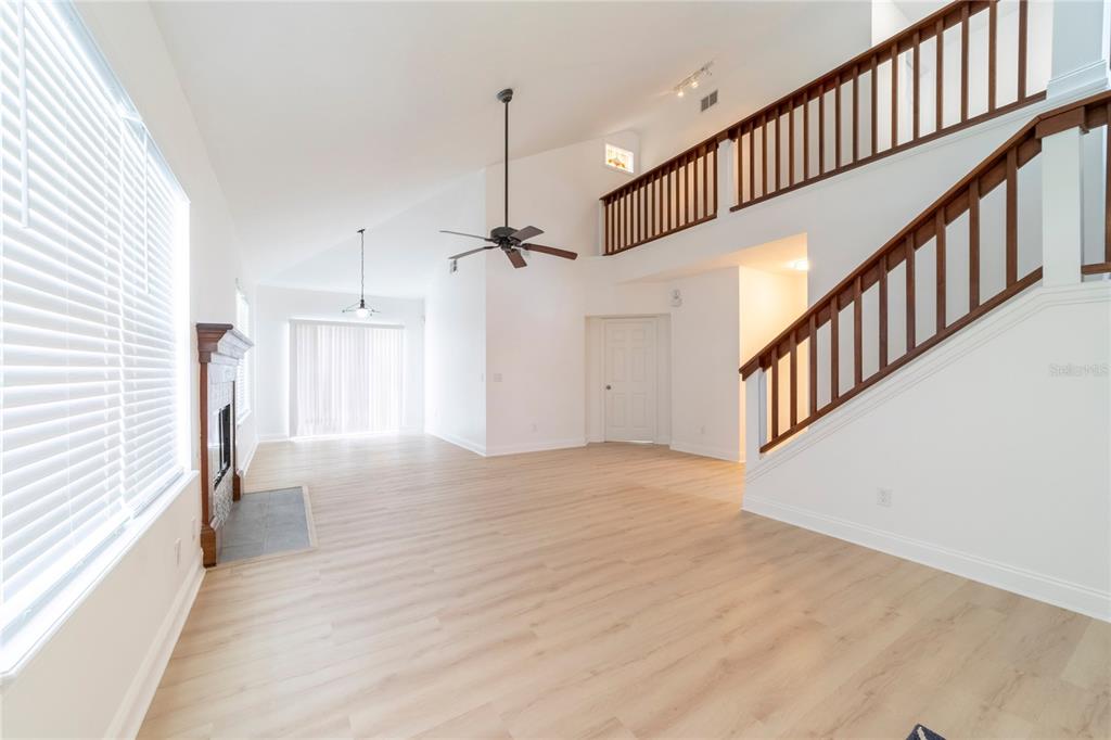 A bright living room features light wood flooring, a fireplace, and a staircase with railings — 499 JULIAN LANE, MAITLAND, FL