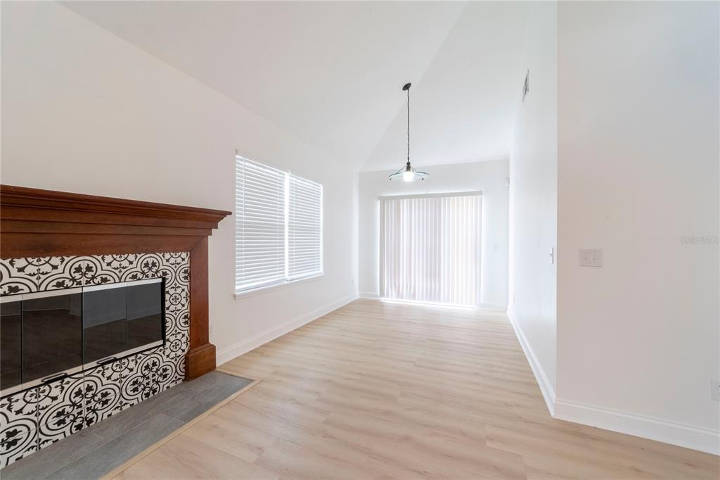 A living room features light wood flooring, a vaulted ceiling, and a tiled fireplace — 499 JULIAN LANE, MAITLAND, FL