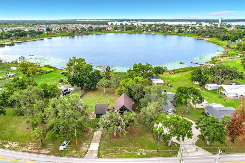 An aerial view shows a house with a steep roof situated on a lakefront lot — 4840 OLD LUCERNE PARK RD, WINTER HAVEN, FL