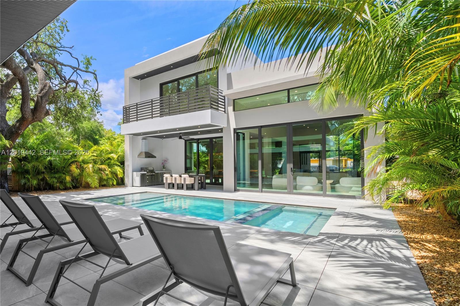 A modern two-story house features a swimming pool, patio lounge chairs, and an outdoor kitchen — 280 NW 47th St, Miami FL 33127, MIAMI, FL