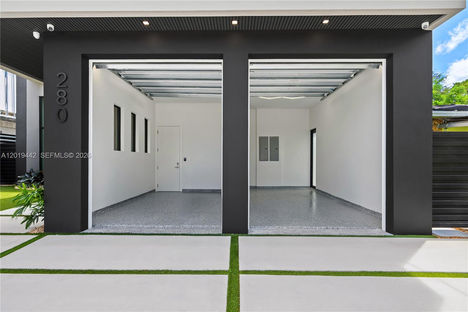A modern two-car garage features white walls, epoxy flooring, and recessed ceiling lighting — 280 NW 47th St, Miami FL 33127, MIAMI, FL